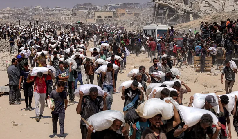 TOPSHOT - People walk with sacks of flour delivered after trucks carrying humanitarian aid entered northern Gaza on July 27, 2025 coming from the Zikim border crossing. (Photo by BASHAR TALEB / AFP) (Photo by BASHAR TALEB/AFP via Getty Images)