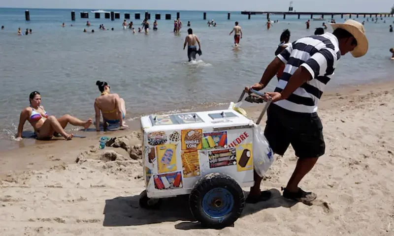 A vendor drags his ice cream cooler across North Avenue Beach in Chicago July 20, 2011. REUTERS/Jim Young/File Photo